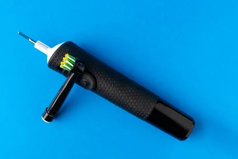 Electric toothbrush. A black toothbrush on a blue background, close up Stock Photos