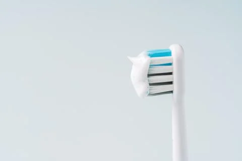Electric toothbrush head with toothpaste against blue background 스톡 사진