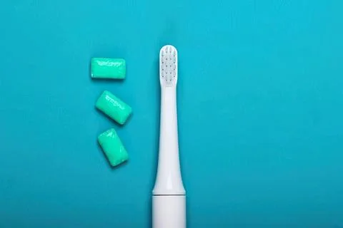 Electric toothbrush with three green toothpaste tablets on blue background Fotos de archivo