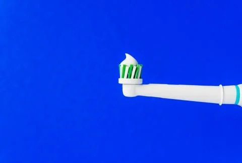 Electric toothbrush with toothpaste on a blue background. Closeup. Isolated. Stock Photos