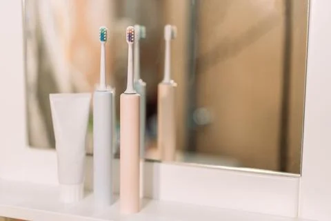 Electric toothbrushes with toothpaste in front of bathroom mirror Stock-Fotos