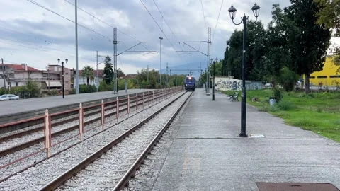 Electric train arriving at a small station in a Greek town Stock Footage 321950434