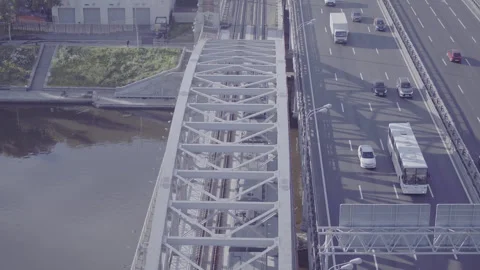 Electric train crossing bridge over river and highway, D-Log footage 库存影片 320802533