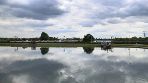 Electric train driving to right around calm water surface Video stock 155789276