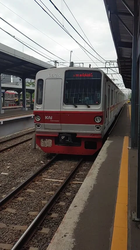 The electric train (KRL) arrives and passes through the platform Stock Footage 277187571