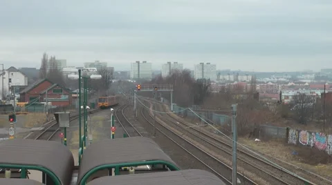 Electric train leaves station heading into the city from bridge over railway Stock Footage 1099397