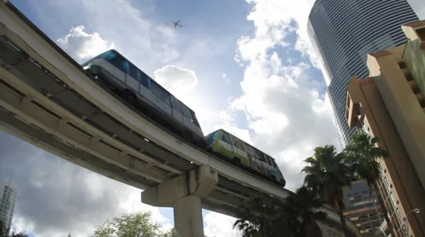 Electric Train passes over with sun flares and plane flying by Stock Footage 36640604