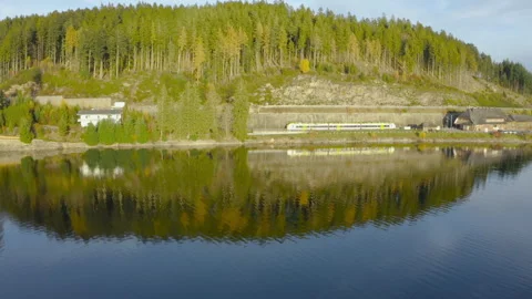 Electric train starting its movement along the shore of a mountain lake surround Stock Footage 321125954