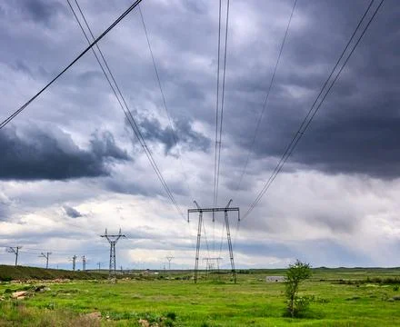 Electric transmission lines under dramatic stormy sky Stock Photos