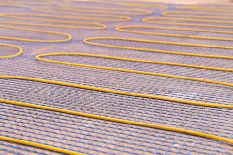 Electric underfloor heating, yellow cable on cement floor. Repair and Stock Photos