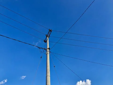 Electric utility pole with multiple cables stretching across a clear sky, s.. Stock Photos