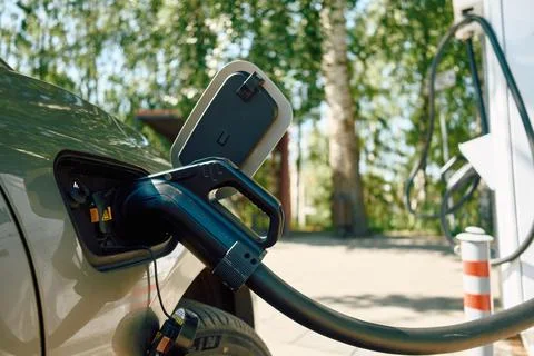 Electric vehicle charging plug inserted into car charging port with sun flare Fotos de archivo