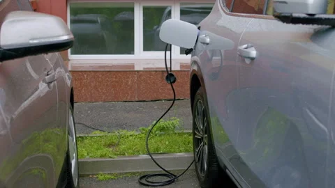 Electric vehicle charging process between two parked cars in a residential area 스톡 동영상 336547518