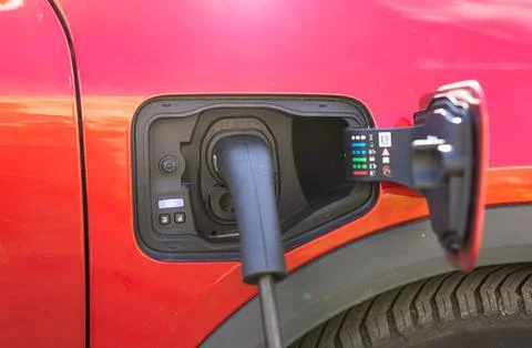 Electric vehicle charging process with plug connected to car port Фото