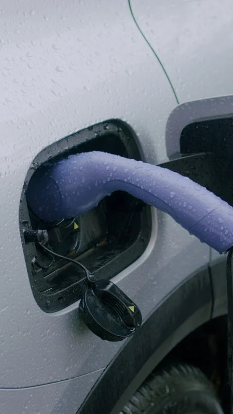 Electric vehicle charging process with purple charging cable inserted into the Stock Footage 337430463