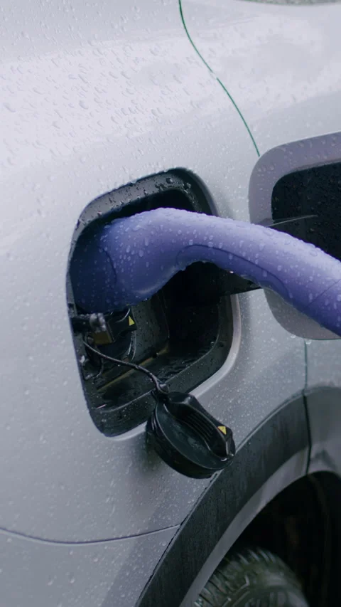 Electric vehicle charging process with purple charging cable inserted into the Stock Footage 337996175