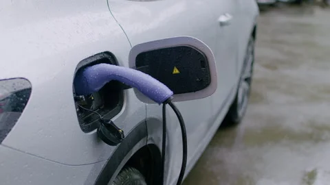 Electric vehicle charging process with purple charging cable connected to car Stock Footage 337998900