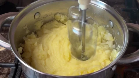 Electric whisk whipping soft mashed potatoes in a stainless steel pot Stock Footage 341510409