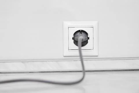 Electric white socket and one plugged in power cord on white wall background Stock Photos