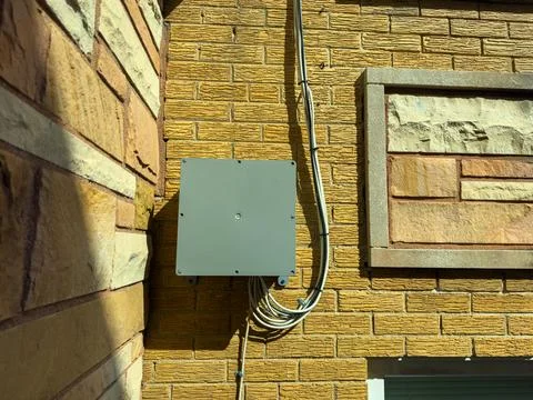 An electrical box is attached to a brick wall of a building. The scene is bri Foto stock