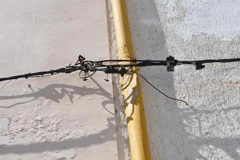 Electrical cables and yellow pipe on a house wall Stock Photos