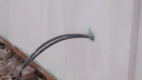 Electrical cables are being fed through a wall opening, showcasing the Video stock 318709591