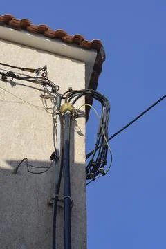 Electrical cables connected to a house facade under blue sky Stock Photos
