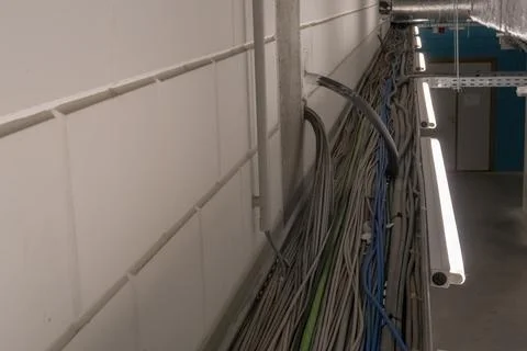 Electrical cables hang from the ceiling in a cable duct Stock Photos