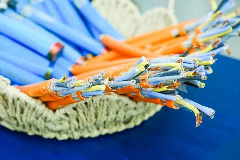Electrical cables inside a wicker basket on a blue background. Industrial copper Stock Photos