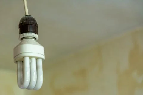 Electrical CFL lamp on barebone socket in old an grunge style room Stock-Fotos