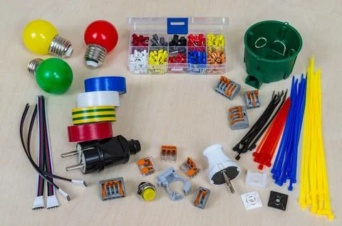Electrical components and parts of different colors on a plywood background. Stock Photos