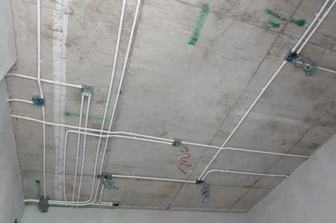 Electrical conduit system installation on exposed concrete ceiling Stock Photos