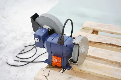 An electrical device for sharpening metal cutting objects stands on a wooden Foto stock