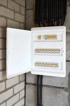 Electrical distribution board open on concrete brick wall with circuit breake Stock Photos