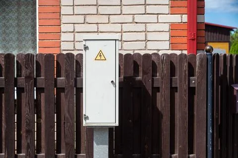 Electrical distribution cabinet sits next to a wooden fence in a residential  Stock Photos