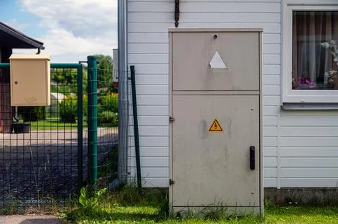 Electrical distribution cabinet stands next to a green fence and a mail box i Stock Photos