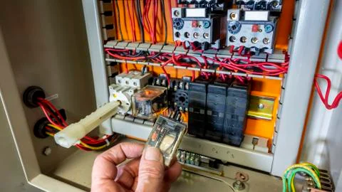 Electrical engineer changing a relay in an old control panel Foto stock