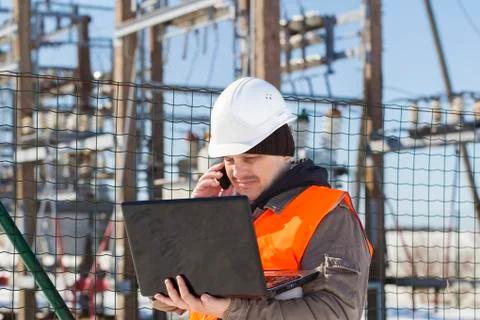 Electrical engineer with computer near the electricity substation Stock Photos