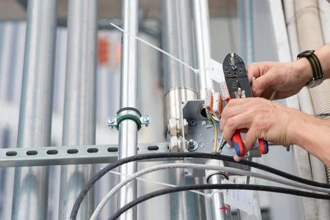 Electrical engineer is engaged in wiring. Removes insulation and connects to Stock Photos