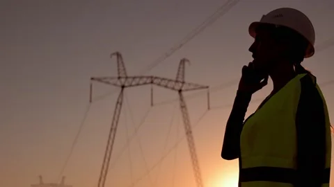 Electrical engineer in hardhat talking on the phone at sunset near the Stockbeeldmateriaal 201032206