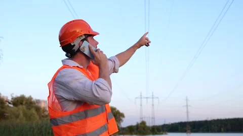 Electrical engineer in helmet checking power line while talking on the phone Stock Footage 252267639