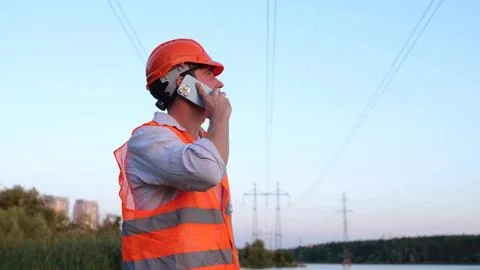 Electrical engineer in helmet checking power line while talking on the phone Stock Photos