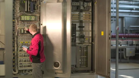 Electrical engineer inspecting industrial control cabinet and circuit breakers a Stock Footage 328607972