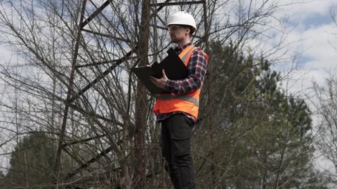 An electrical engineer inspects the power line and writes down the data in a log Stock Footage 240458993