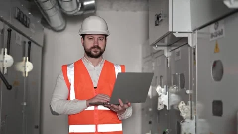 Electrical Engineer Inspects Switchboard with Laptop in Industrial Setting Stock-Footage 297292501