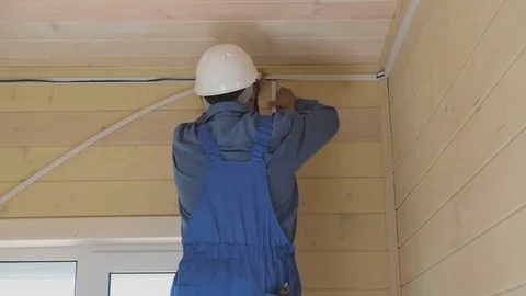 Electrical engineer performs installation of ceiling light in a new wooden house Stock Footage 111052154