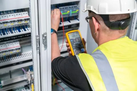 An electrical engineer performs a measurement in a control cabinet Stock Photos
