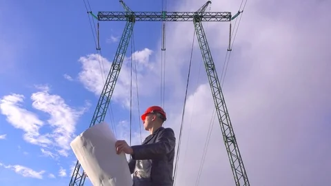 Electrical engineer with a plan of electric grids in the hands near power lines Stock Footage 74904871