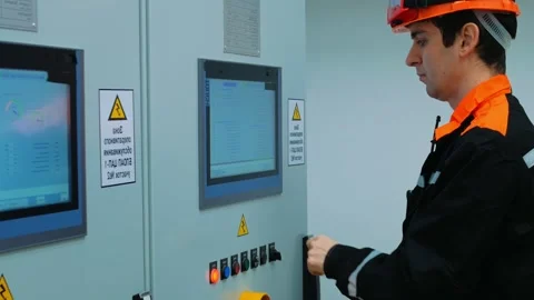 Electrical engineer in safety helmet is programming control panel at industrial Stock Footage 285653280