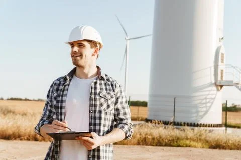 An electrical engineer standing on a field with windmills Stock Photos